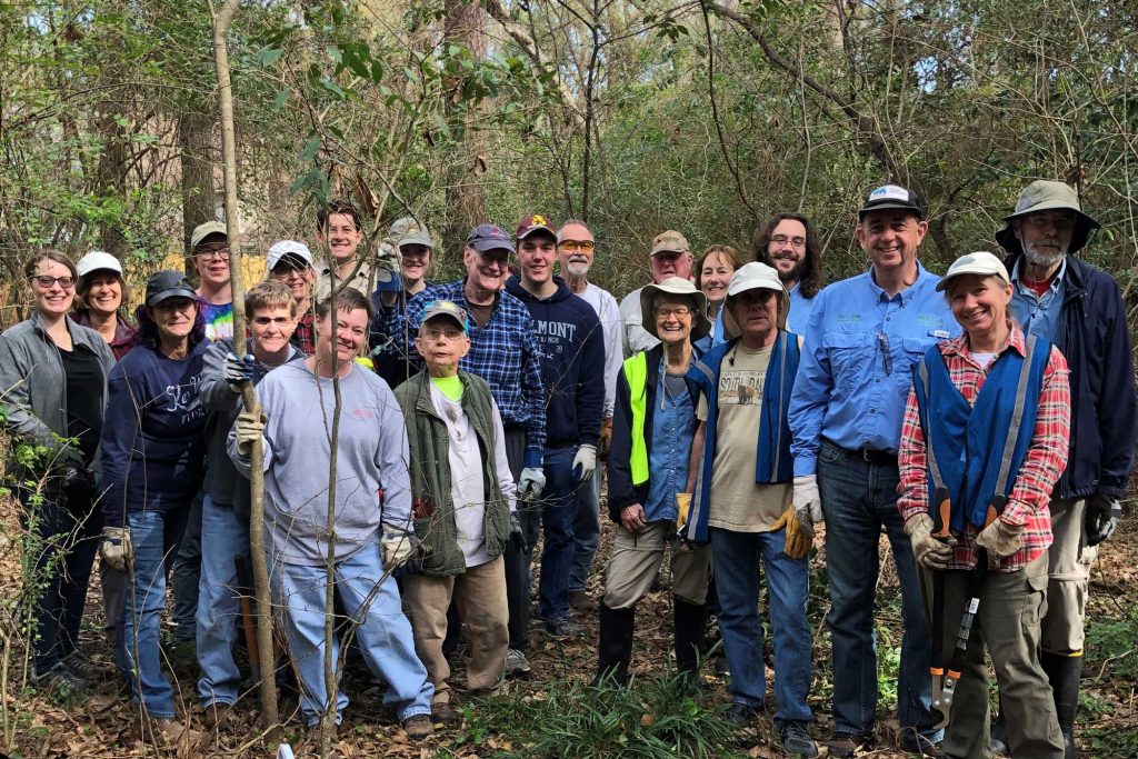 Invasives Task Force of The Woodlands volunteers stand in work clothes in a woodland area.