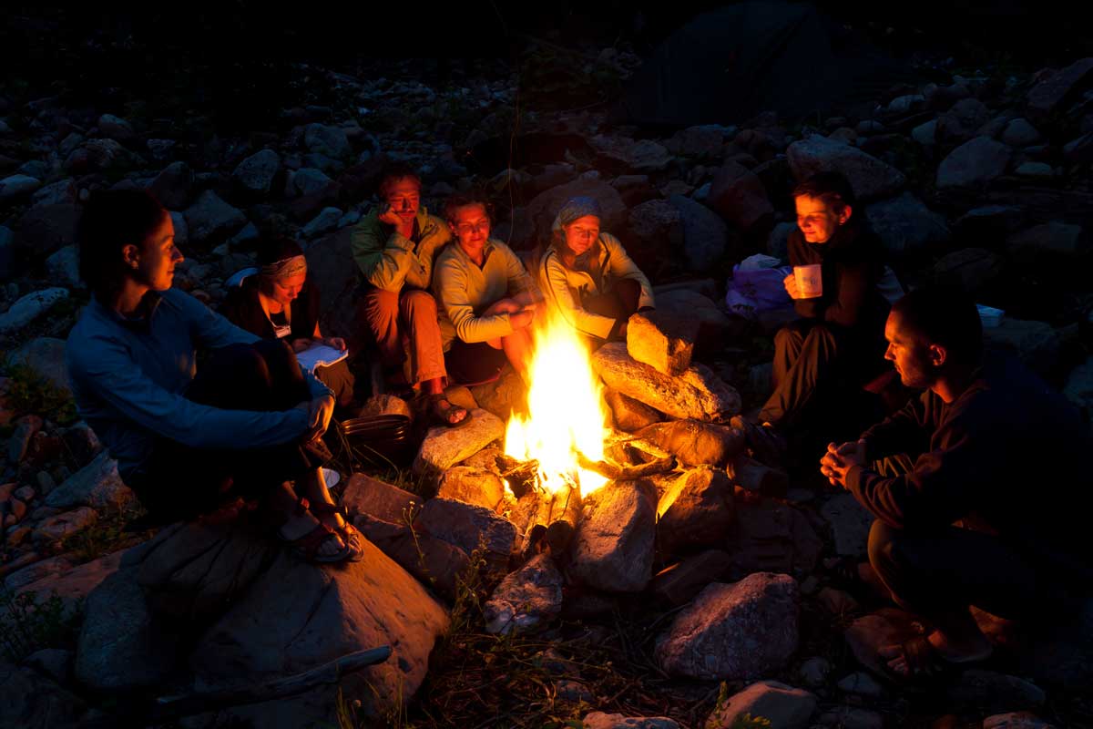 group of people sitting on rocks around a camp fire